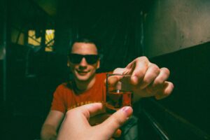 man in brown crew neck t-shirt holding clear drinking glass