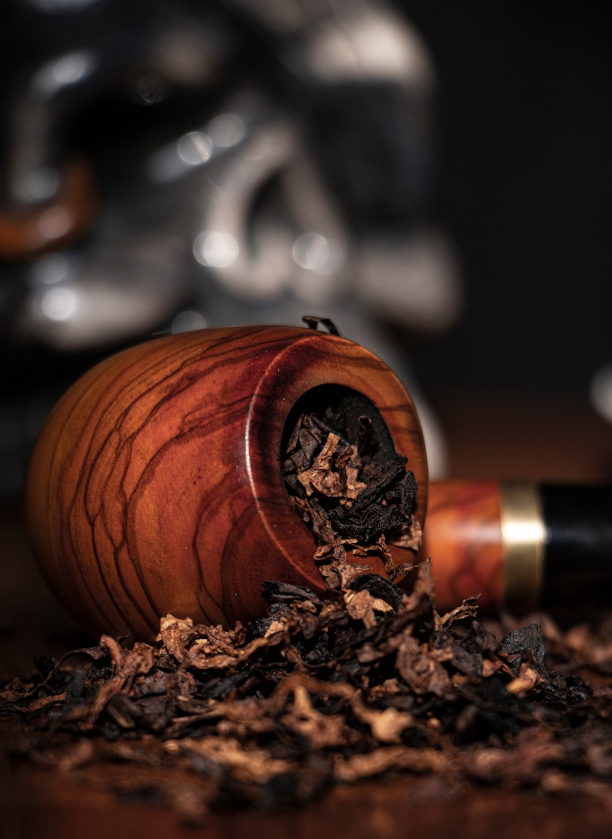 brown wooden round pipe on its side spilling out tobacco