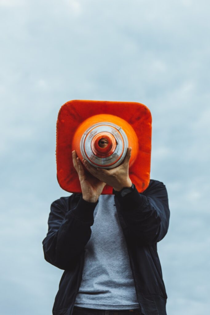 person in black jacket holding orange and gray camera